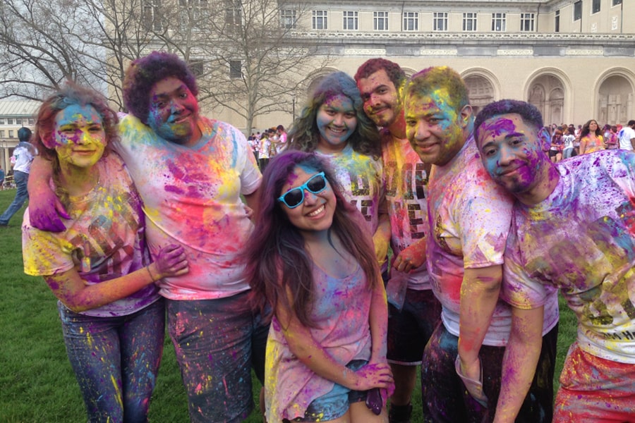 Students covered in brightly colored paint from a Holi celebration pose on The Cut.