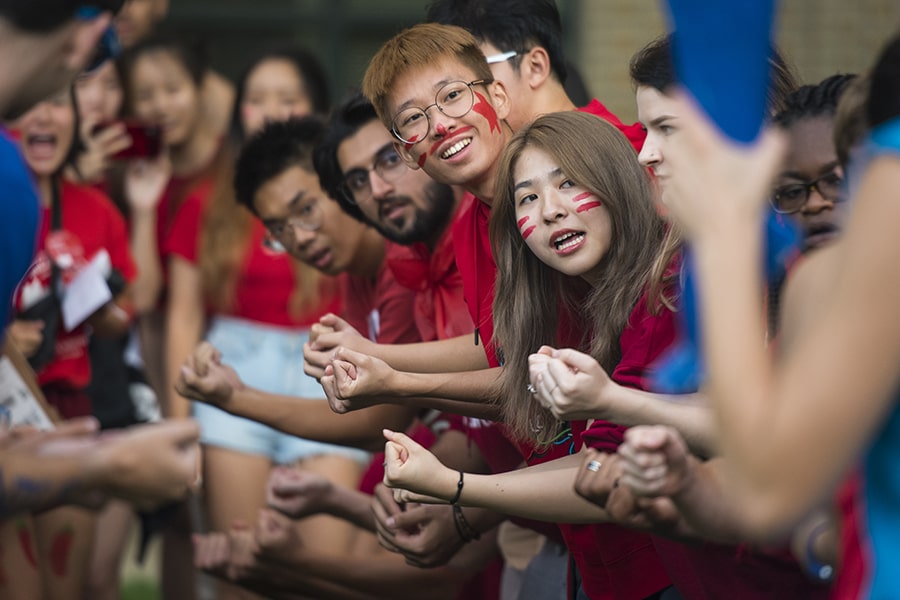 Students in face paint and matching t-shirts chant at orientation.