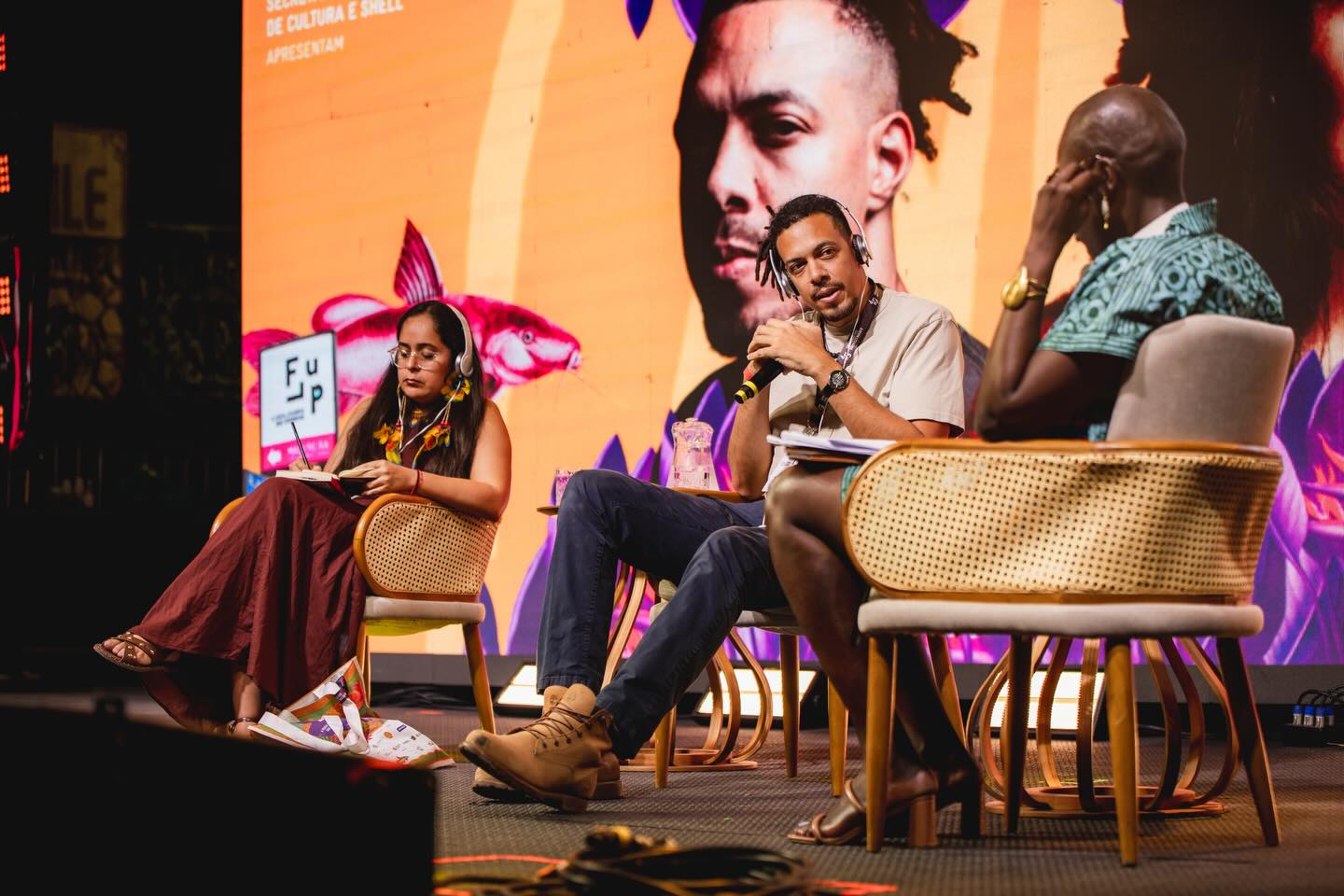 figures sit on a stage holding a discussion