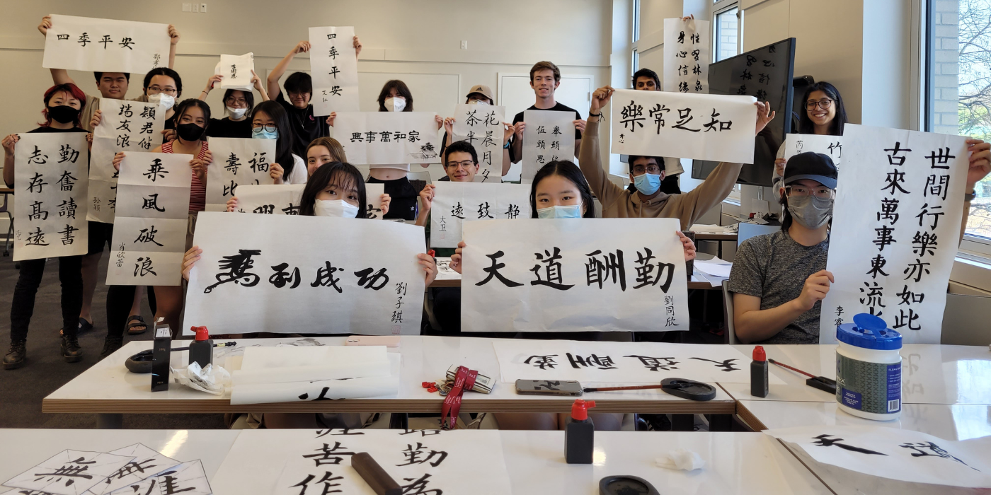 Students hold up examples of their Chinese calligraphy work