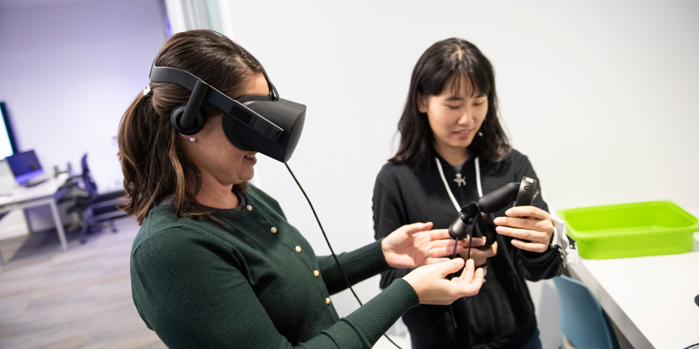 Two students play with a virtual reality headset in the Kenner Room