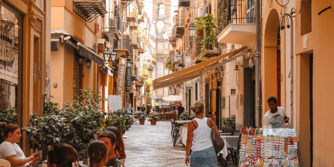 A woman walks down a busy alley in Italy