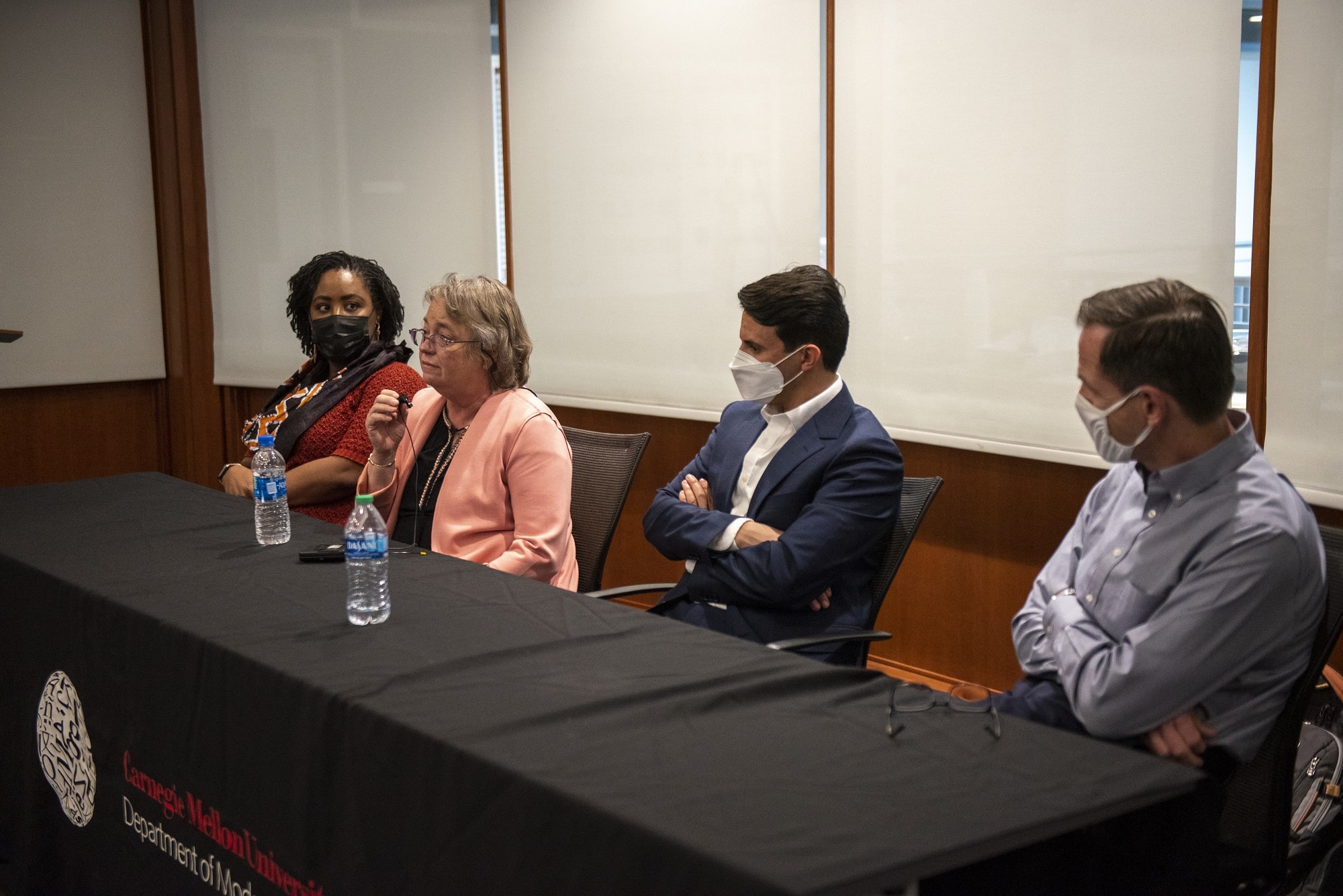 Panelists Uju Anya, Celeste Kinginger, Khaled Al Masaeed, and Dan Dewey seated at a table during a Q&A session