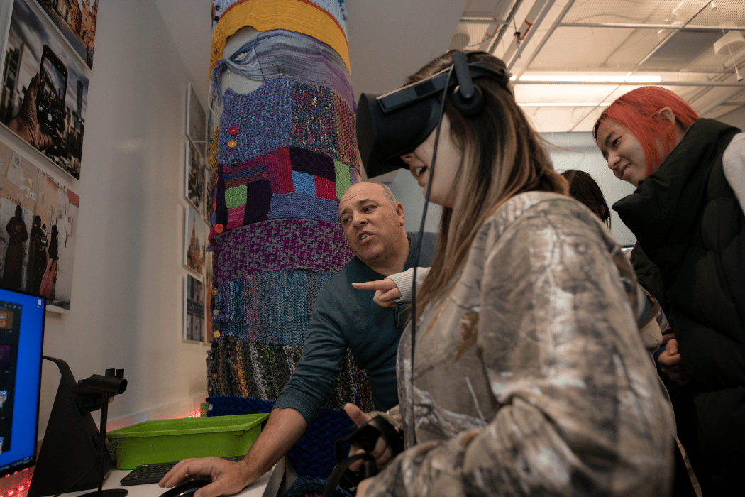 A group of students and faculty observe as one person tries a VR headset.