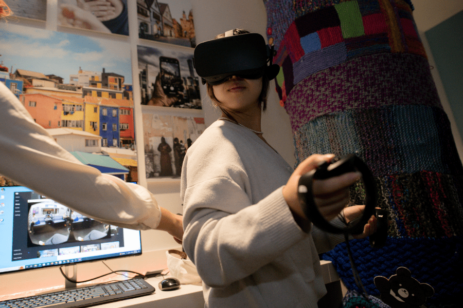 Students uses VR headset and remotes in a dark room