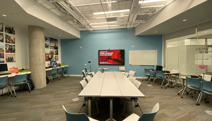 A room is set up with large desks and several computer monitors. The room is colorful and is set up to encourage collaboration.