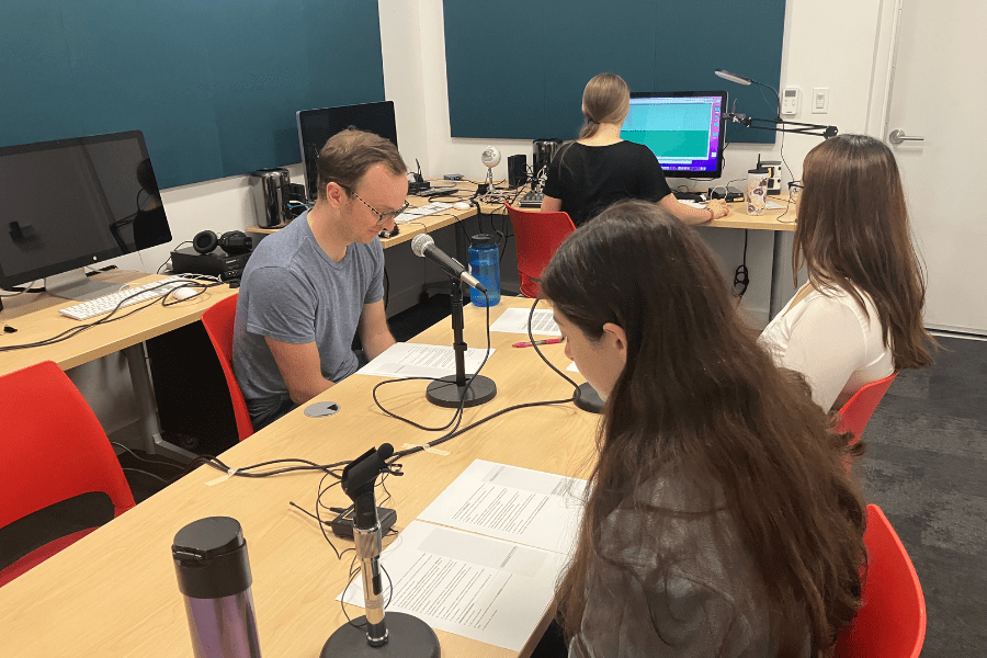 Four people sit in a computer lab.