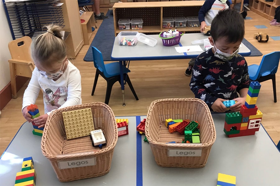 Children wearing masks, playing with Legos