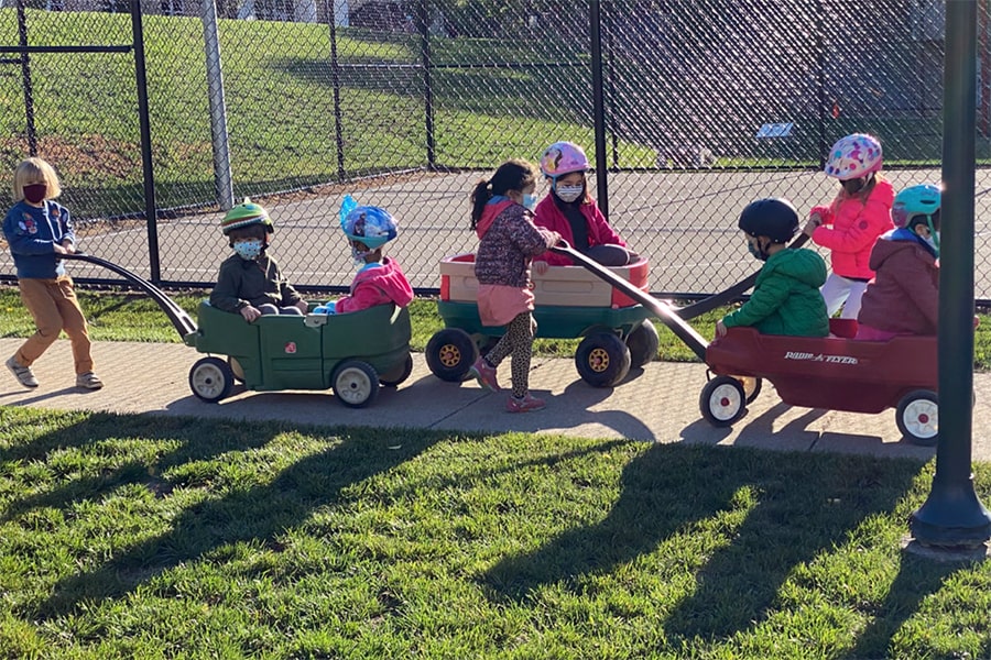 Children wearing masks, riding in wagons