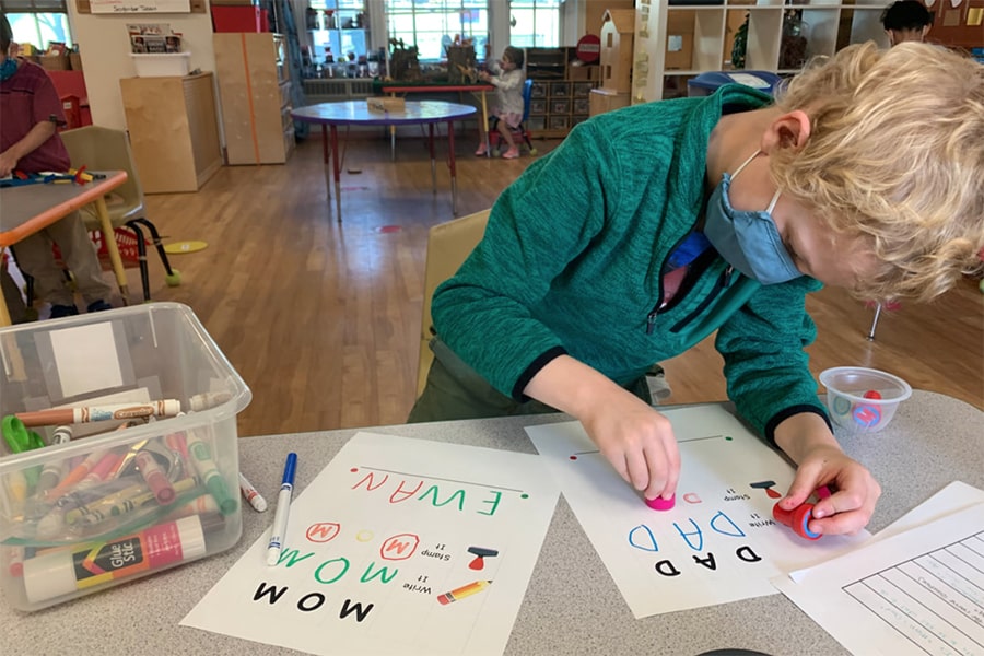 Child wearing a mask, learning letters