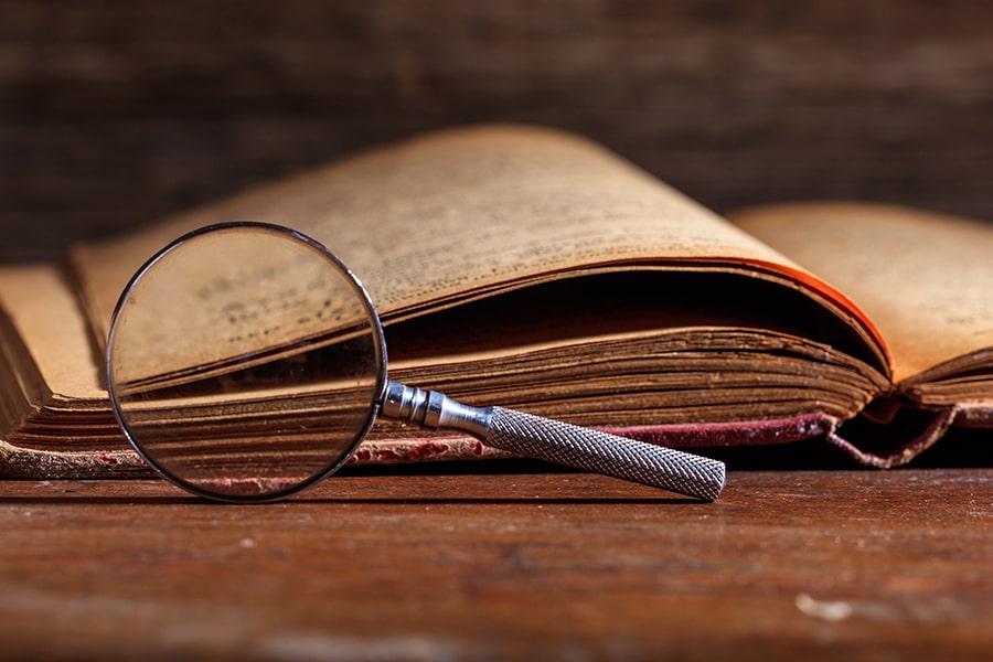 An open book and magnifying glass on a table