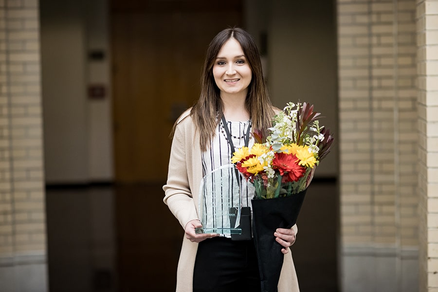 Ashley Christopherson poses with her Community Excellence Award and a bouquet of flowers.