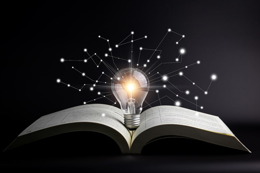 An illustration of an open book with a lightbulb above it