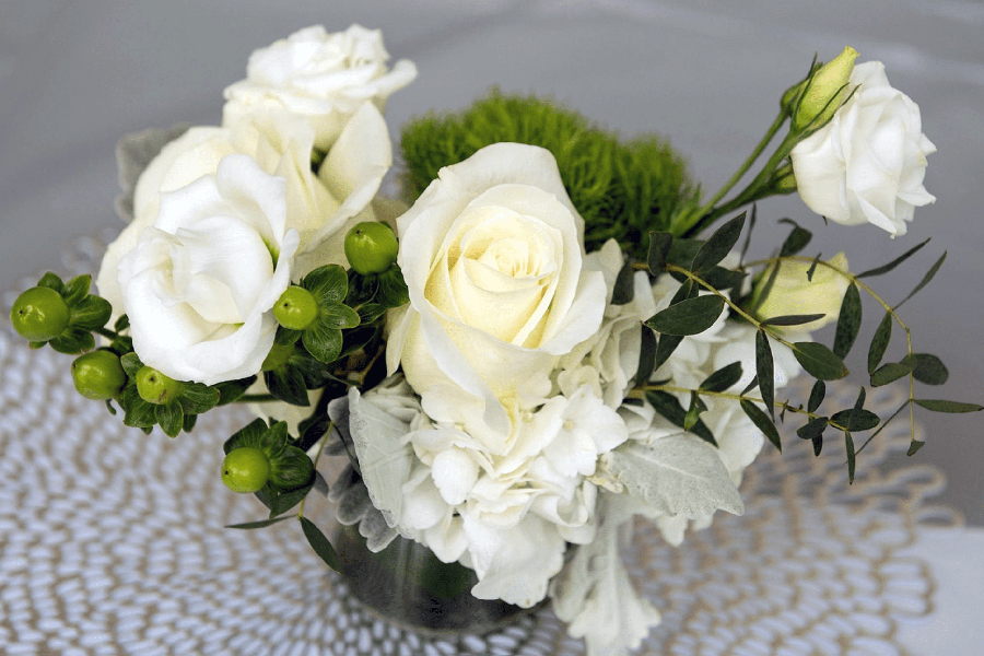 A bouquet of white flowers on a lace table cloth.