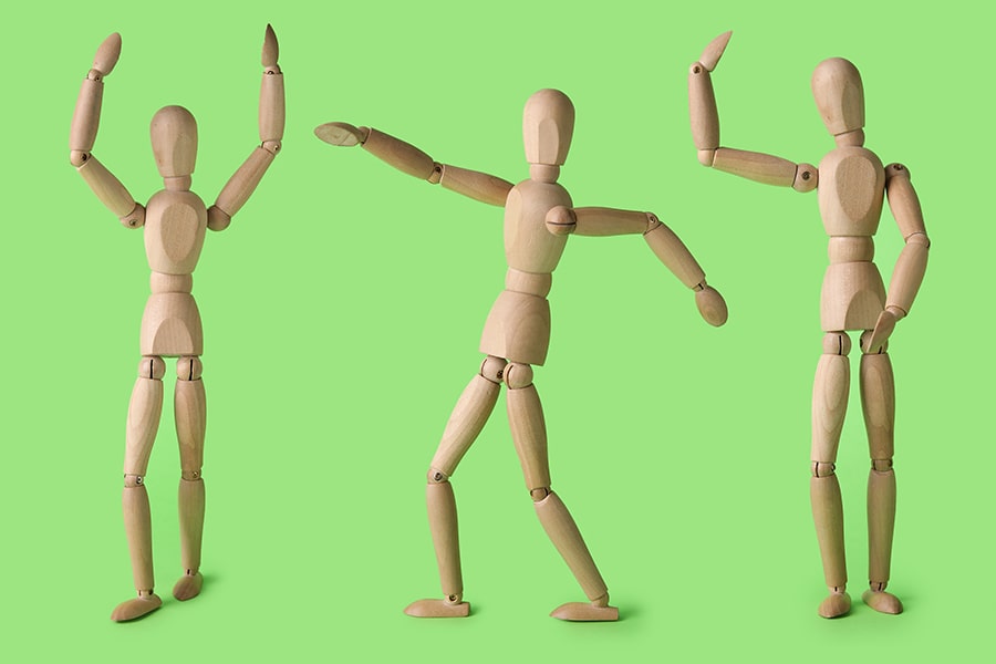 Wooden models of human figures in various positions on a green background