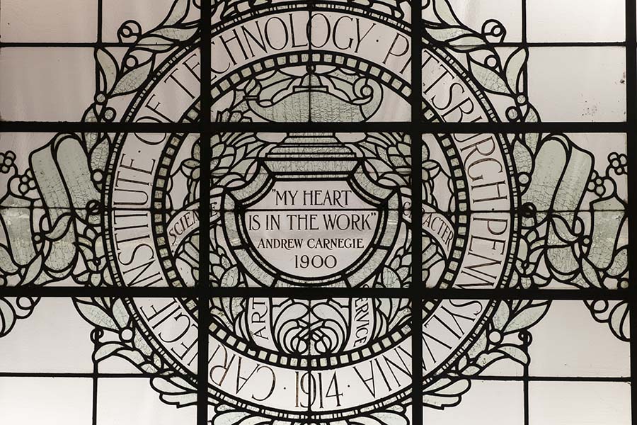 A view of a leaded glass ceiling in Baker Hall that reads "My Heart is in the Work, Andrew Carnegie 1900"