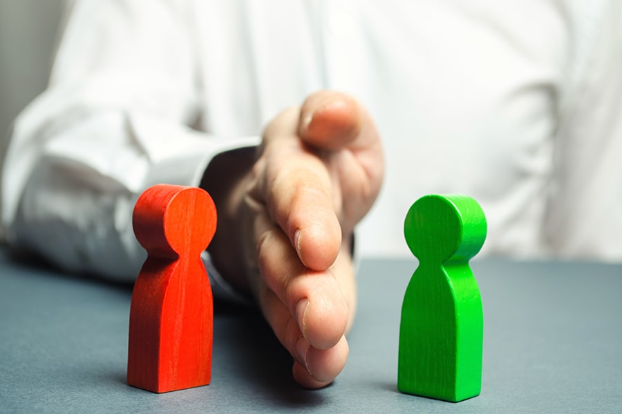 A person with their hand placed between two wooden people