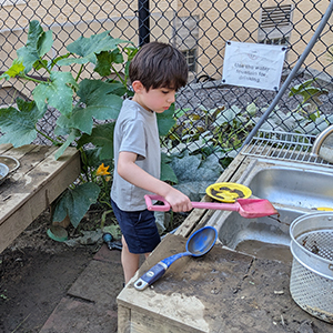 A student playing in the mud kitchen
