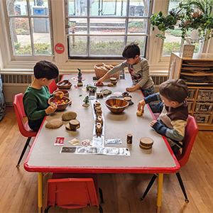 A group of students plying with wooden vehicles on a table
