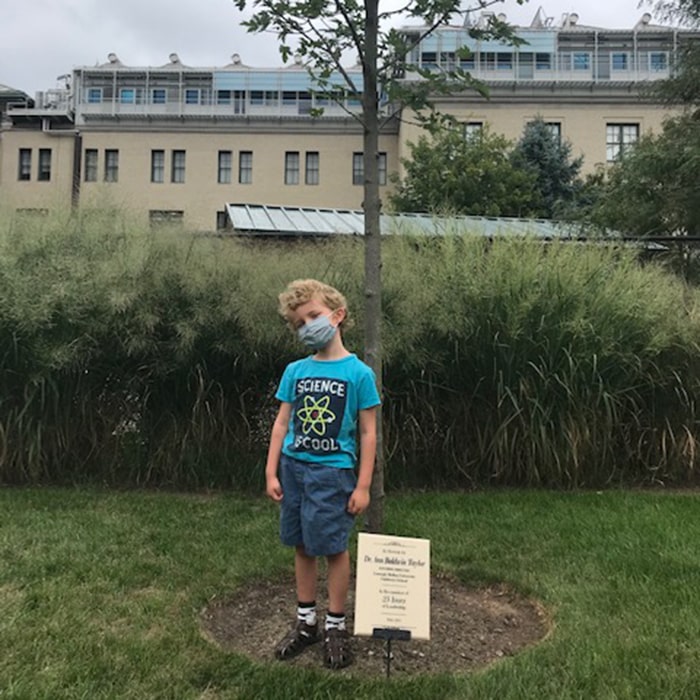 Great grandson, Wyatt, with the playground tree dedicated to Dr. Ann Baldwin Taylor at the 50th Anniversary Celebration in 2018.