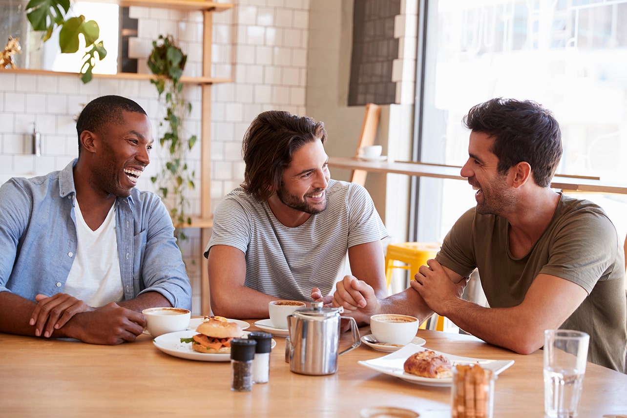 three men chat at a table in a coffee shop