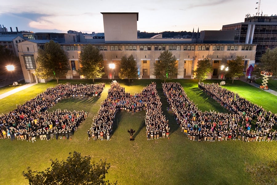 Students assembled in the shape of the letters C, M and U on the grassy mall