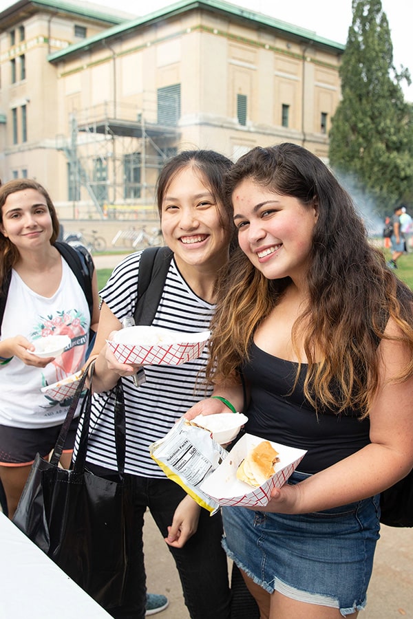 Three students pose on The Cut with hotdogs.