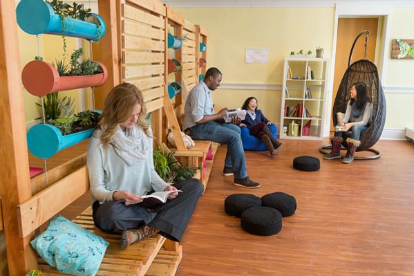 Students meditate in a serene room surrounded by plants and pillows.