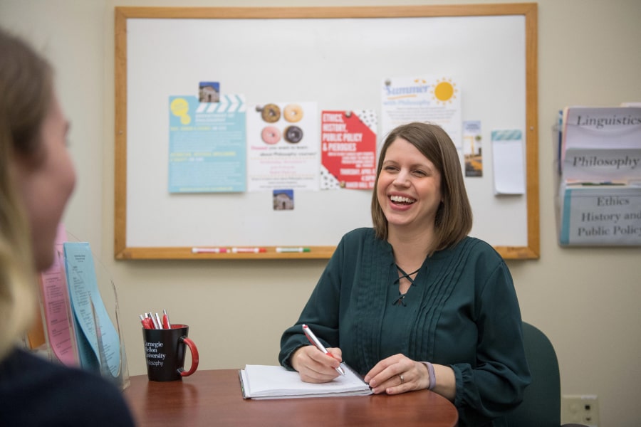 An academic advisor laughs with a student.
