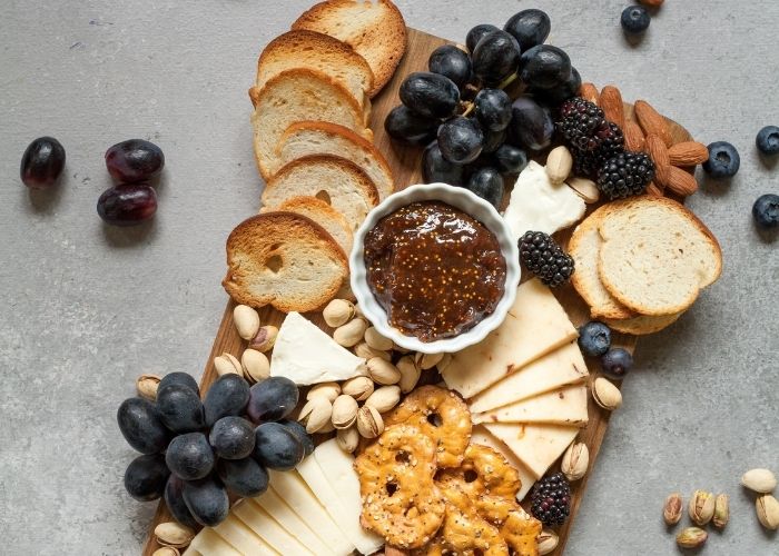 charcuterie board with cheese, grapes and pretzel thins