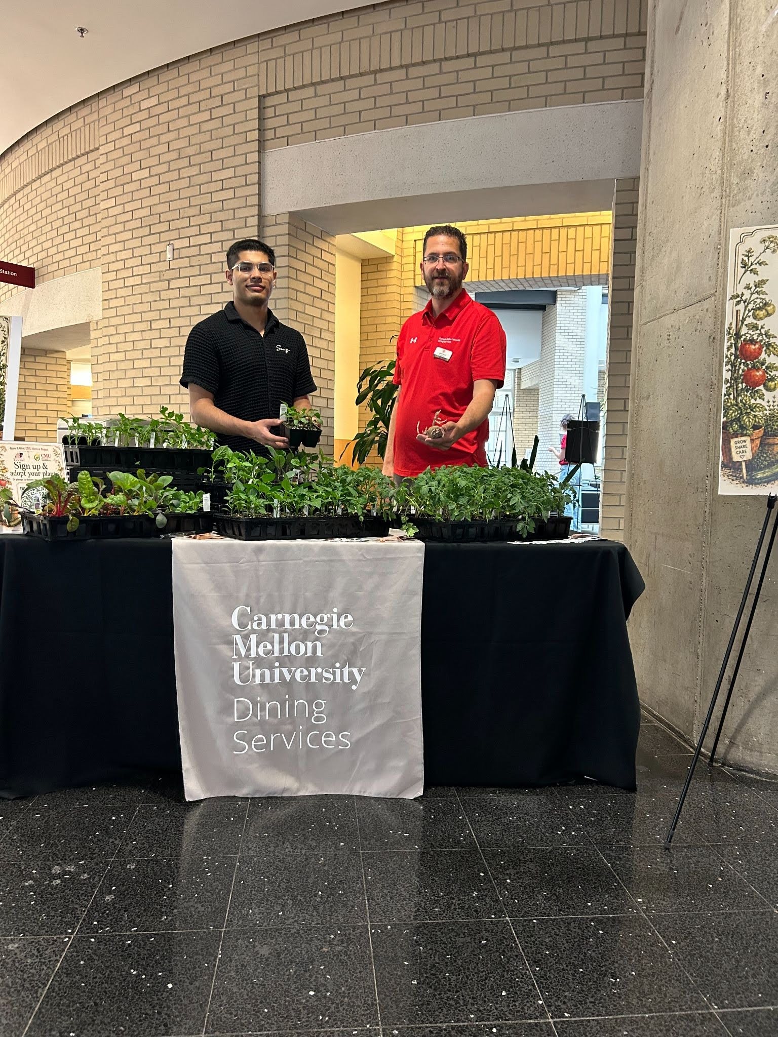 Two Dining staff standing at table in front of seedling plants