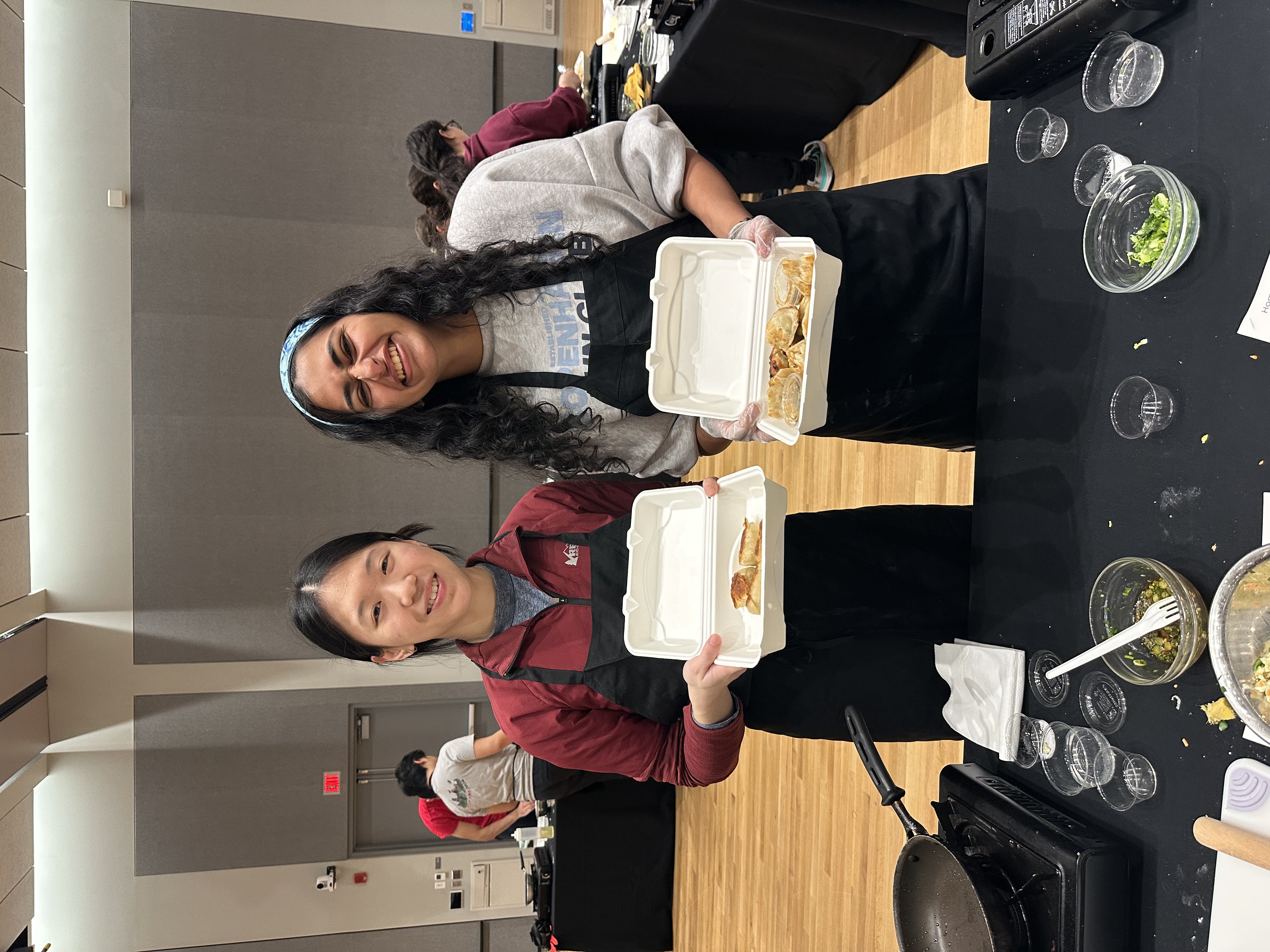 two students holding takeout containers of food
