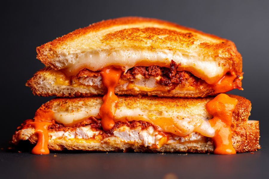 Toasted chicken sandwich with melted cheese dripping out of the bread