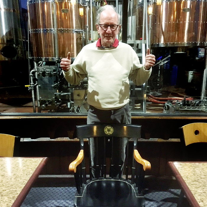 Don Casey, an alumnus, poses with his father Dan's commemorative chair