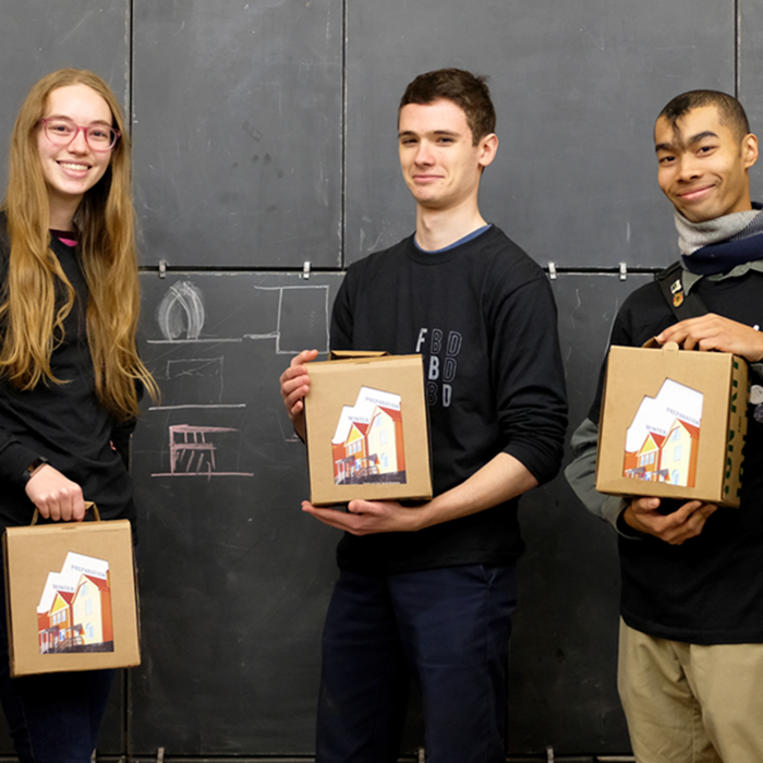 Three students hold boxes for the community