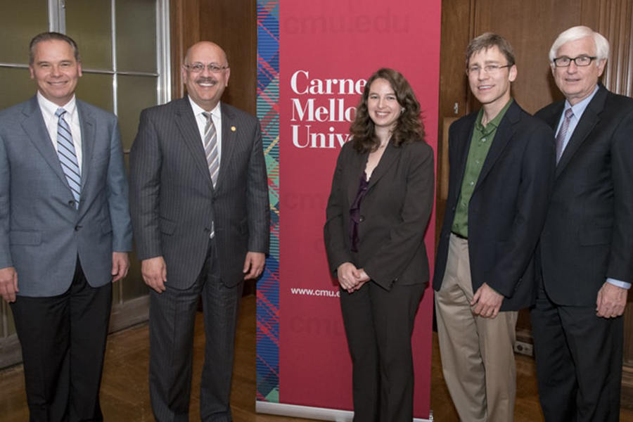 A photo of five people standing in front of a CMU sign. To the left of the sign are two men in suits, the one on the right being Farnam Jahanian. In front of and to the right of the sign are three formally dressed professors