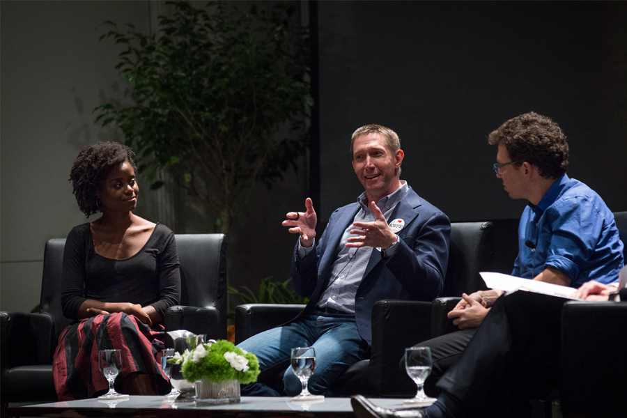 Three people sitting in armchairs, with the two people on the sides listening attentively to the person in the middle who is talking