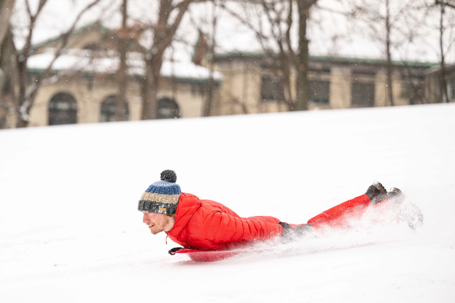 young man sledding in the snow down a hill