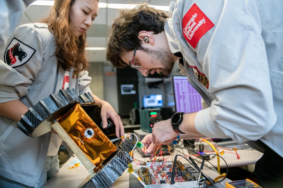 research students giving the number one sign with a robotic rover on the floor
