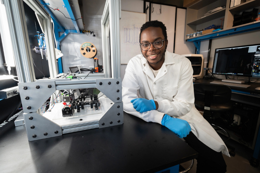 young man in a lab setting with a lab coat and gloves on