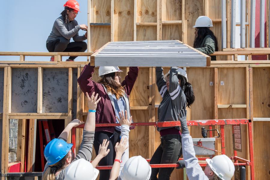 students working together to raise a ladder
