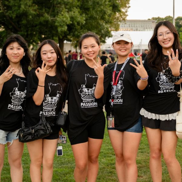 a group of 5 first-year students pose, holding up their fingers in a W for their housing community