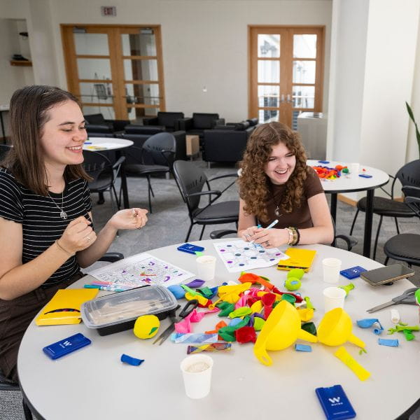 two students play with fidget toys while enjoying a conversation