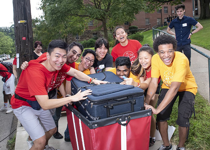 Photo of student volunteers smiling around a red cart on Move-In Day