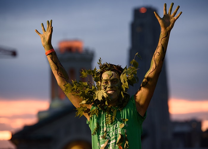 a student dressed in green with his hands in the air