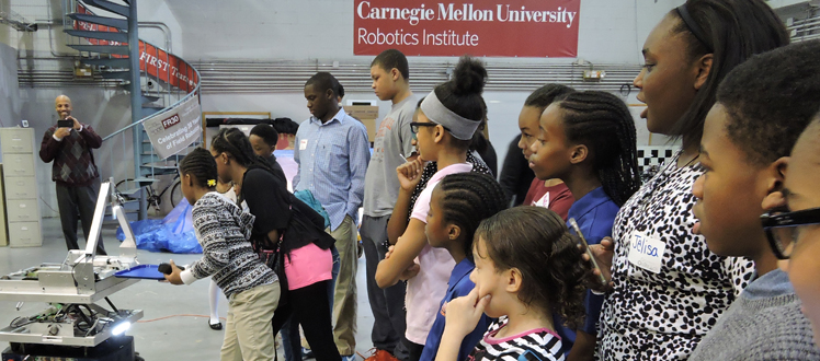 Students with their teacher looking at a robotics institute demonstration.