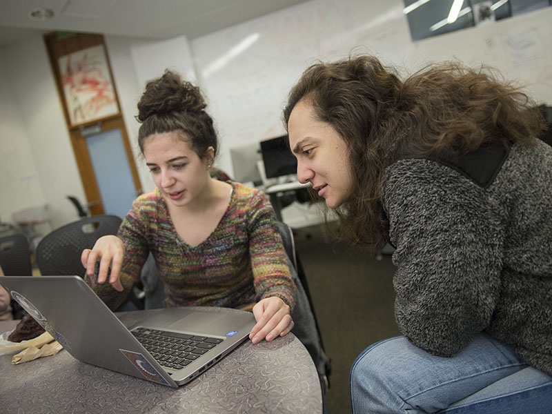 Two SCS students work on a laptop