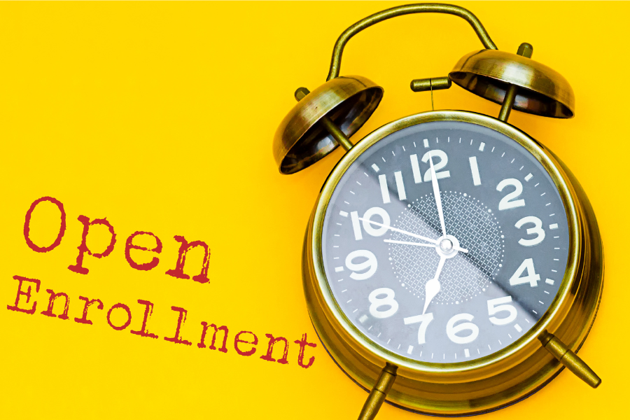 an old fashioned gold clock sits against a yellow background, the hour and minute hands indicate 7:00. There is text on the screen that reads "open enrollment" 