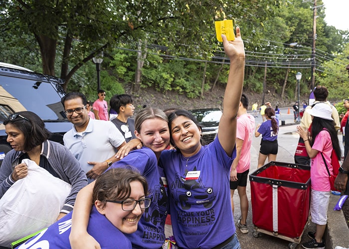 three student wearing purple helping students move into mudge house
