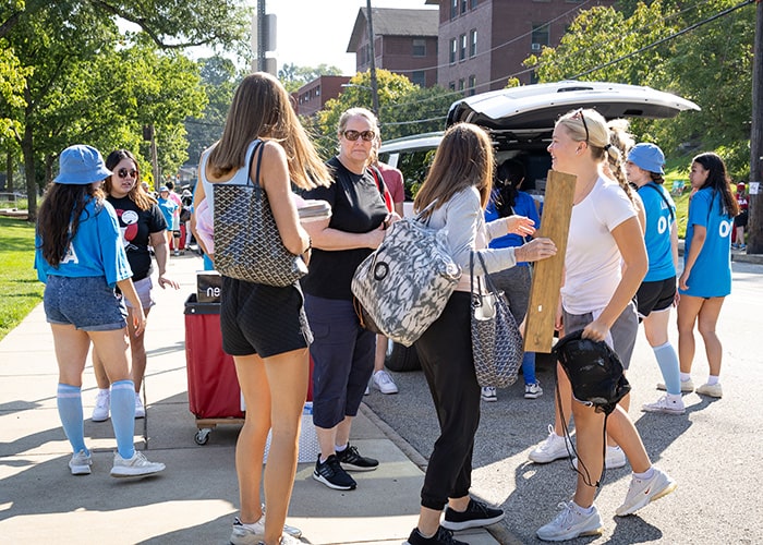 students dressed in blue help unload a car
